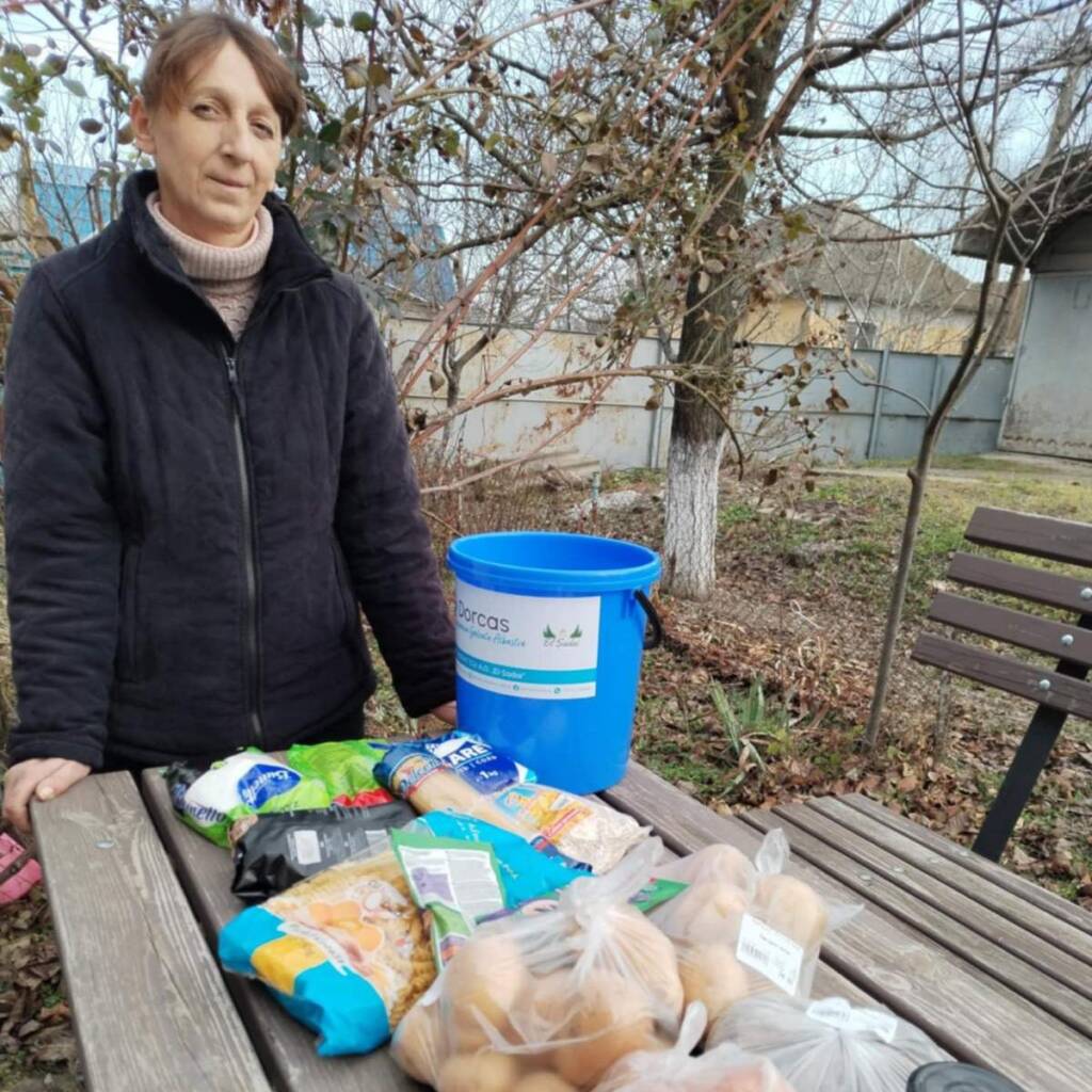 Frau mit blauem Dorcas-Eimer und Lebensmitteln
